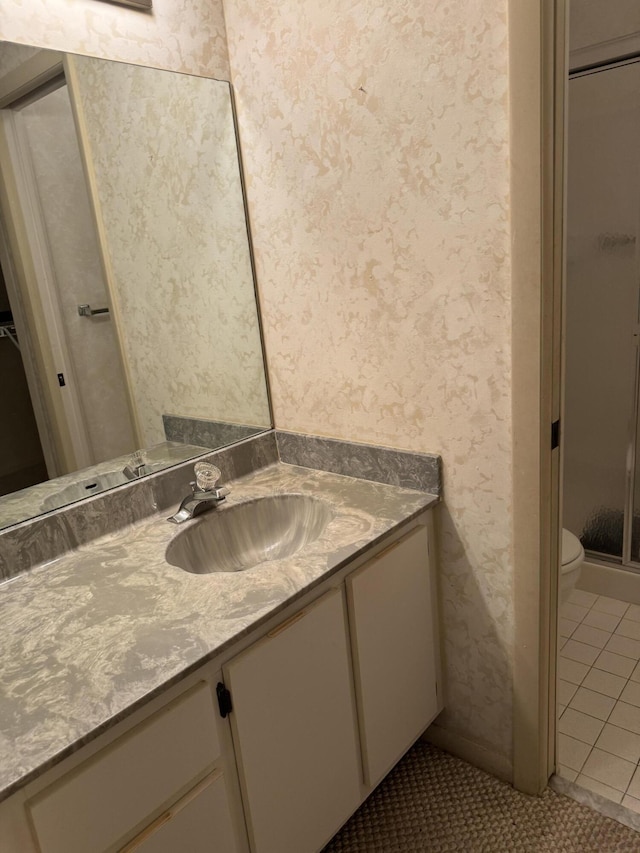 bathroom featuring vanity, a shower with door, tile patterned floors, and toilet