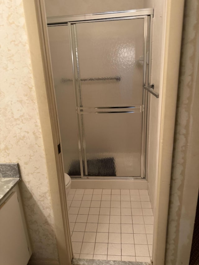 bathroom featuring tile patterned flooring, vanity, a shower with shower door, and toilet