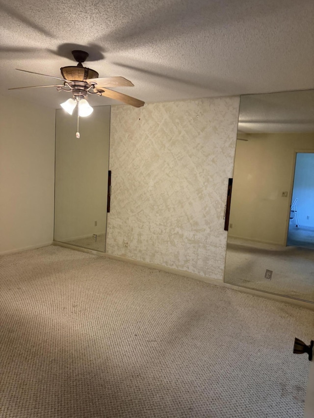 carpeted empty room with ceiling fan and a textured ceiling