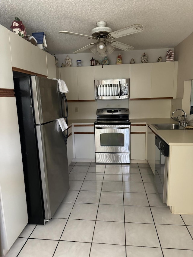 kitchen with light tile patterned flooring, sink, ceiling fan, stainless steel appliances, and cream cabinets