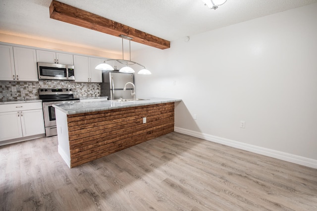 kitchen with pendant lighting, appliances with stainless steel finishes, light hardwood / wood-style flooring, light stone countertops, and beam ceiling