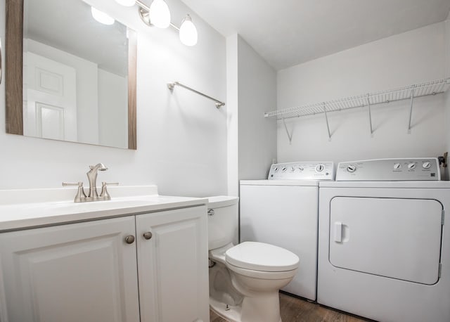 bathroom with hardwood / wood-style flooring, vanity, toilet, and washing machine and clothes dryer