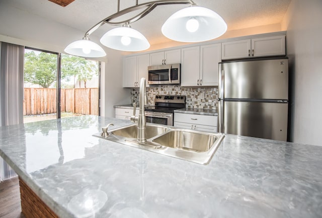 kitchen with tasteful backsplash, stainless steel appliances, a textured ceiling, and decorative light fixtures