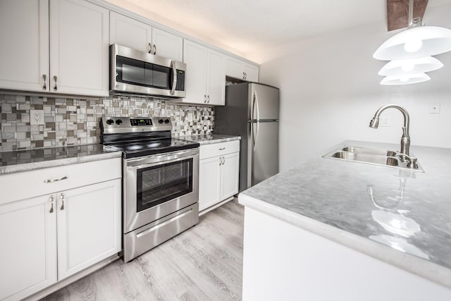 kitchen featuring sink, white cabinets, light hardwood / wood-style flooring, stainless steel appliances, and tasteful backsplash