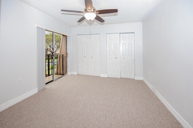 unfurnished bedroom with light carpet, access to exterior, two closets, and ceiling fan