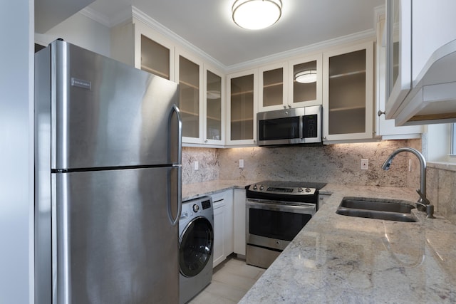 kitchen featuring white cabinets, tasteful backsplash, stainless steel appliances, and washer / clothes dryer