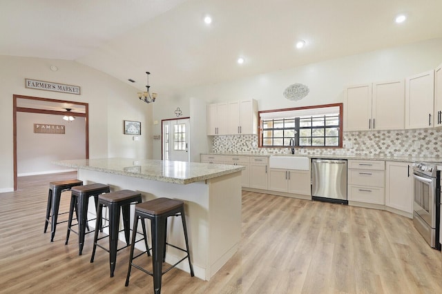 kitchen featuring white cabinetry, vaulted ceiling, a center island, and appliances with stainless steel finishes