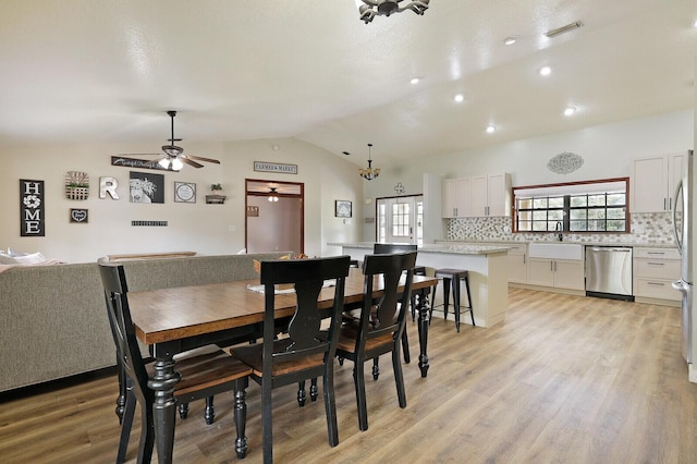 dining area featuring sink, vaulted ceiling, ceiling fan, and light wood-type flooring