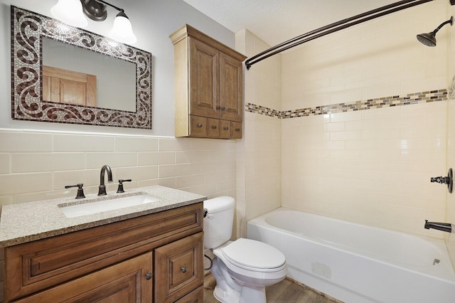 full bathroom featuring toilet, tile walls, vanity, tiled shower / bath combo, and hardwood / wood-style floors