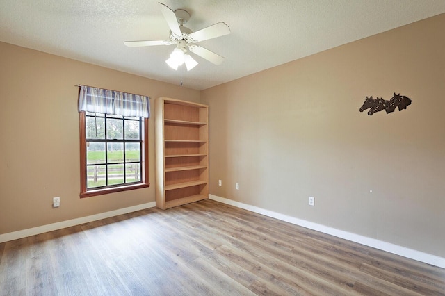 spare room featuring ceiling fan, light hardwood / wood-style flooring, and a textured ceiling