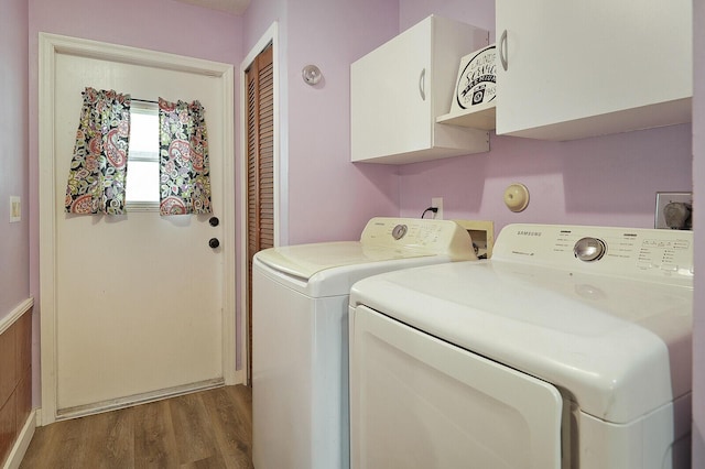 clothes washing area with hardwood / wood-style floors, washer and clothes dryer, and cabinets