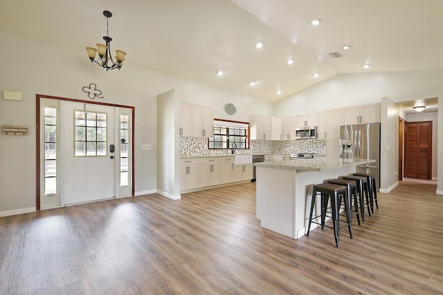 kitchen with white cabinetry, a center island, hanging light fixtures, appliances with stainless steel finishes, and backsplash