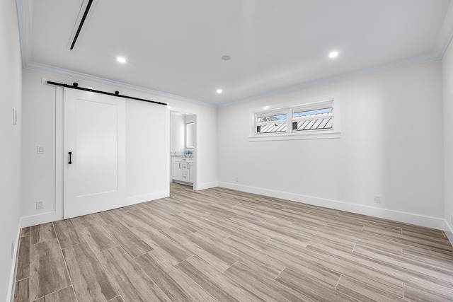 unfurnished bedroom featuring a barn door, crown molding, and light hardwood / wood-style floors