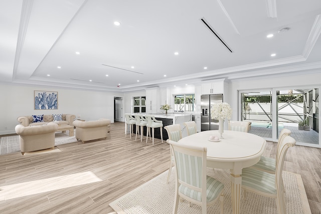 dining room with ornamental molding, light hardwood / wood-style flooring, and a tray ceiling