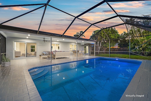 pool at dusk with a patio, an outdoor hangout area, a lanai, and ceiling fan