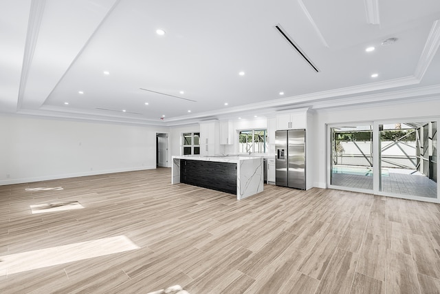 kitchen with stainless steel fridge, white cabinetry, light hardwood / wood-style floors, and a kitchen island