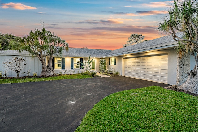 ranch-style home with a garage and a yard