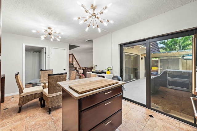 kitchen featuring a kitchen island, light tile flooring, a notable chandelier, and dark brown cabinetry