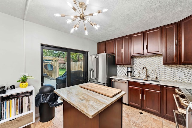 kitchen with premium appliances, backsplash, light tile flooring, an inviting chandelier, and sink