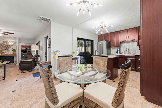 dining room with light tile floors, a textured ceiling, and ceiling fan with notable chandelier