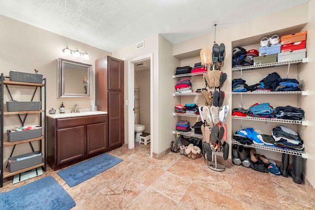 bathroom with toilet, a textured ceiling, tile floors, and vanity with extensive cabinet space