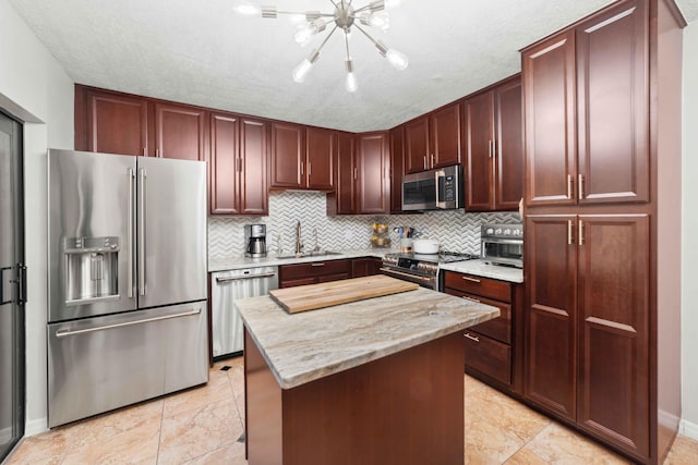 kitchen with premium appliances, light tile floors, sink, backsplash, and light stone counters