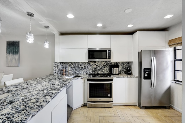 kitchen with hanging light fixtures, white cabinets, light parquet floors, backsplash, and stainless steel appliances