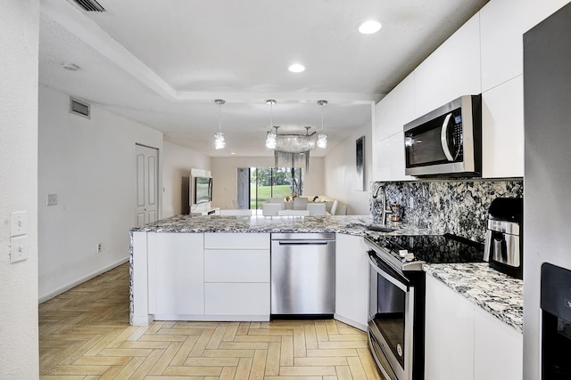 kitchen with decorative light fixtures, stainless steel appliances, white cabinets, and light parquet floors