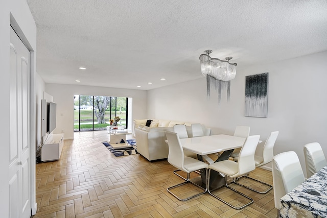 dining space featuring light parquet flooring, a textured ceiling, and a notable chandelier