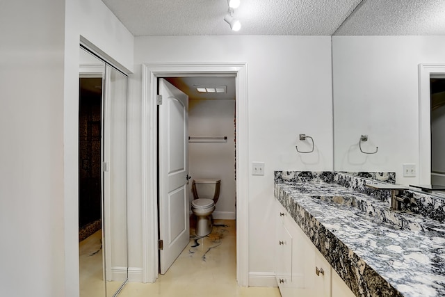 bathroom featuring vanity, a textured ceiling, and toilet