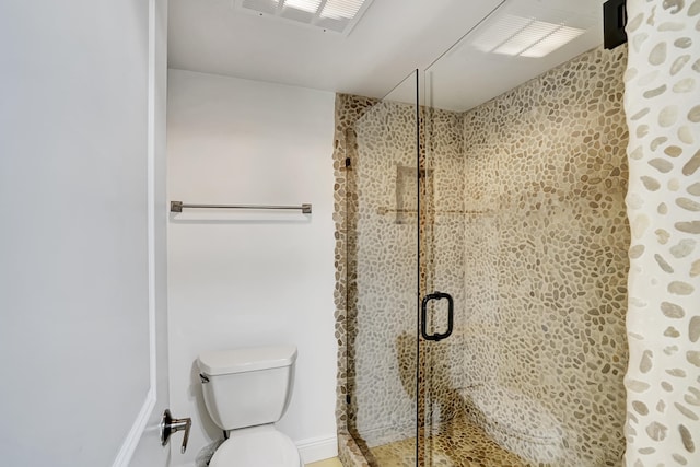 bathroom featuring a shower with shower door and toilet