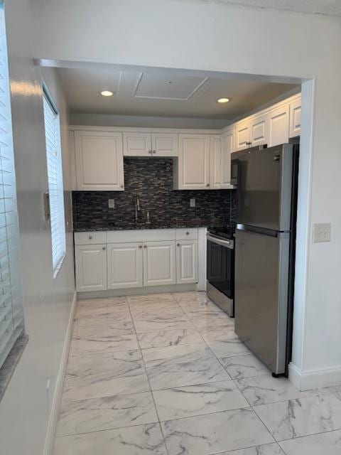 kitchen featuring electric stove, freestanding refrigerator, marble finish floor, white cabinetry, and a sink