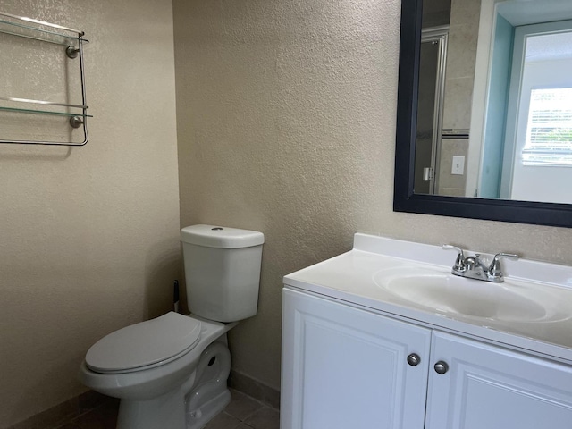 bathroom with a textured wall, vanity, and toilet