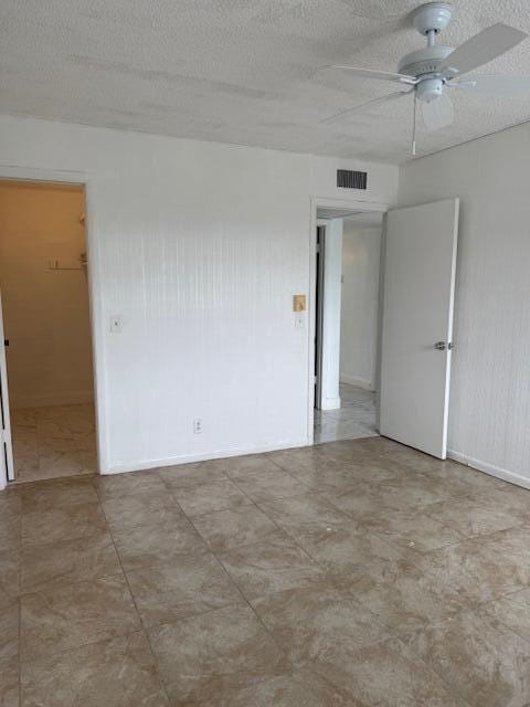 unfurnished room featuring visible vents, ceiling fan, and a textured ceiling