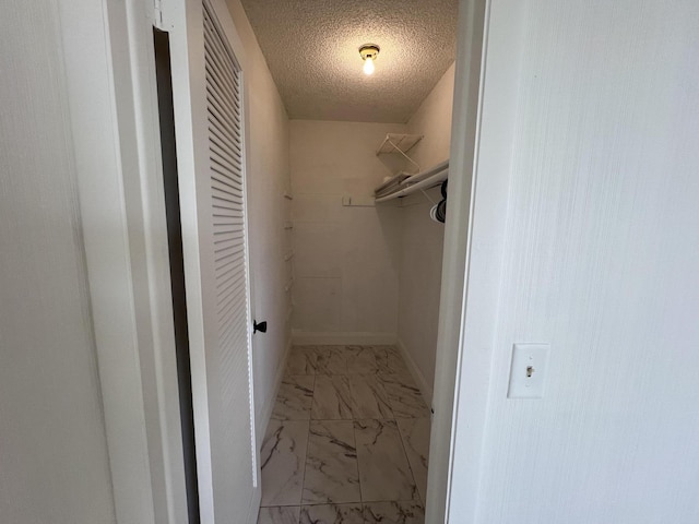 walk in closet featuring marble finish floor