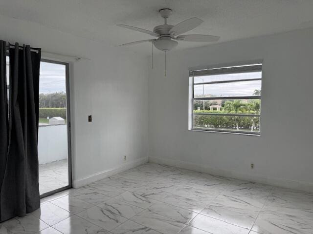 empty room featuring ceiling fan, marble finish floor, and baseboards