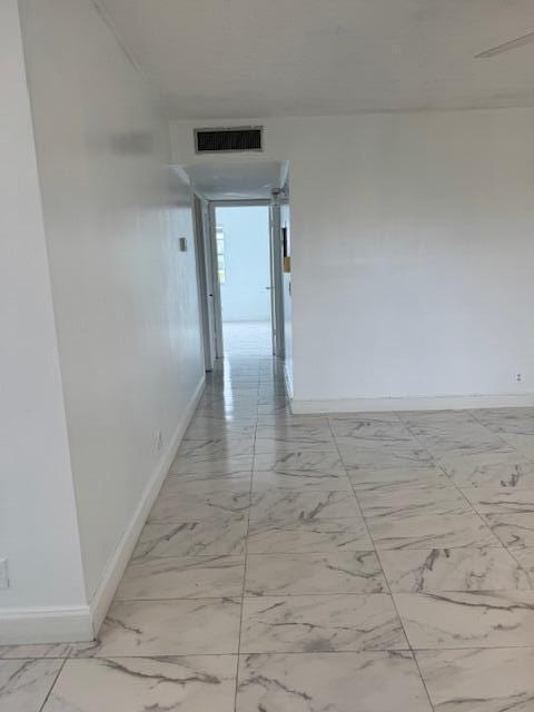 corridor with marble finish floor, visible vents, and baseboards