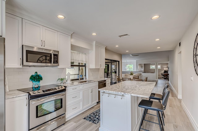 kitchen featuring a kitchen breakfast bar, light stone countertops, tasteful backsplash, and stainless steel appliances