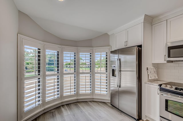 kitchen with light hardwood / wood-style floors, light stone countertops, tasteful backsplash, appliances with stainless steel finishes, and white cabinetry