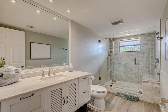 bathroom featuring a shower with door, toilet, vanity with extensive cabinet space, and hardwood / wood-style flooring