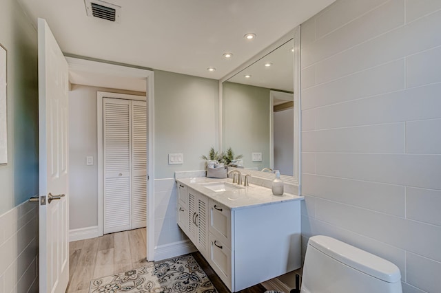 bathroom featuring hardwood / wood-style floors, large vanity, toilet, and tile walls