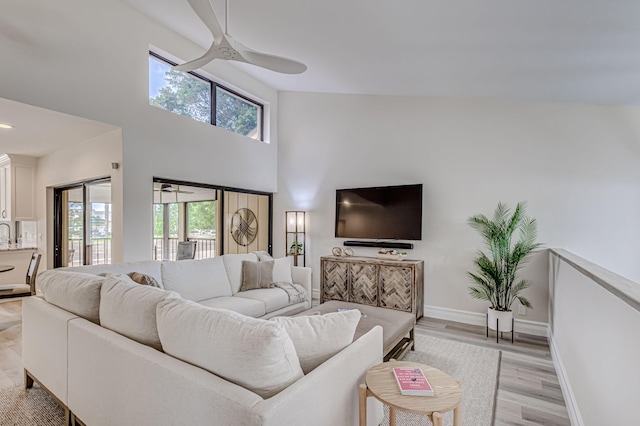 living room with light hardwood / wood-style floors, ceiling fan, and high vaulted ceiling