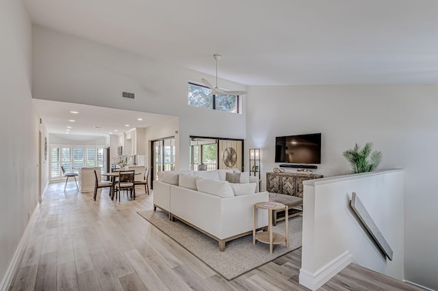 living room with high vaulted ceiling, a wealth of natural light, and light wood-type flooring