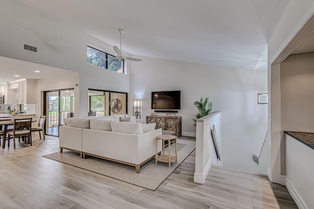 living room featuring high vaulted ceiling, light hardwood / wood-style floors, and ceiling fan