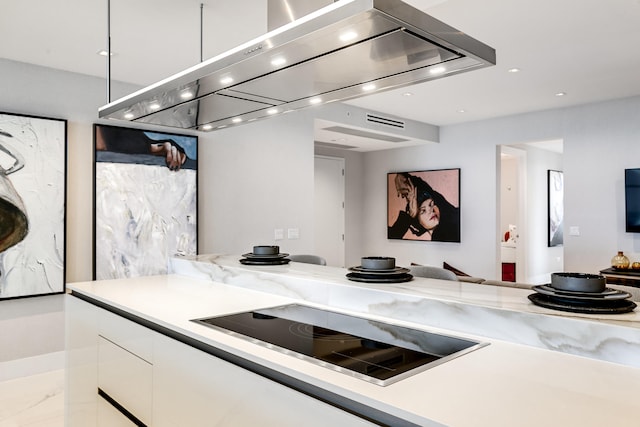 kitchen featuring island range hood, light stone countertops, washer / clothes dryer, white cabinetry, and black electric stovetop