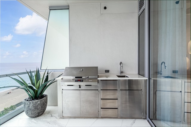 view of patio featuring a balcony, an outdoor kitchen, sink, and a water view