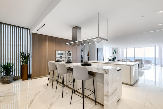 kitchen with a center island, light tile flooring, expansive windows, a breakfast bar, and a water view