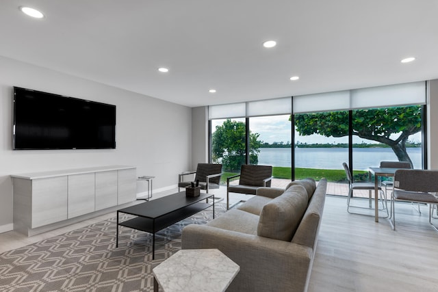 living room featuring floor to ceiling windows, a water view, and light hardwood / wood-style flooring