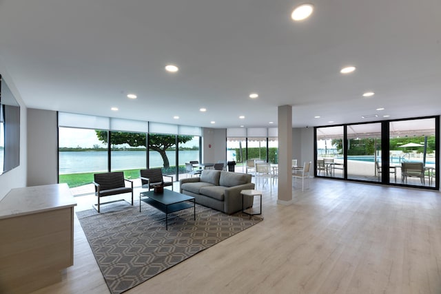 living room with french doors, a water view, expansive windows, and hardwood / wood-style flooring