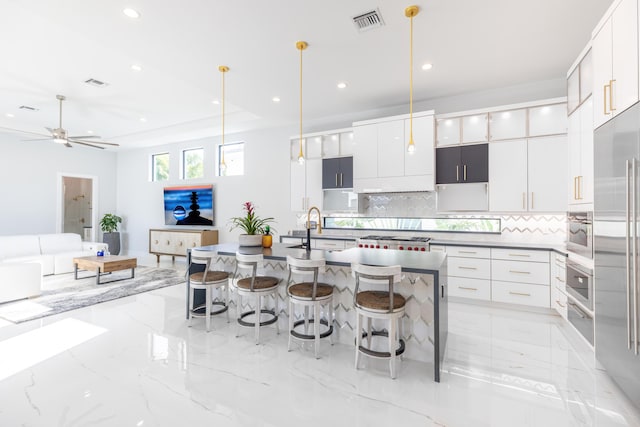 kitchen featuring decorative backsplash, ceiling fan, sink, white cabinetry, and hanging light fixtures